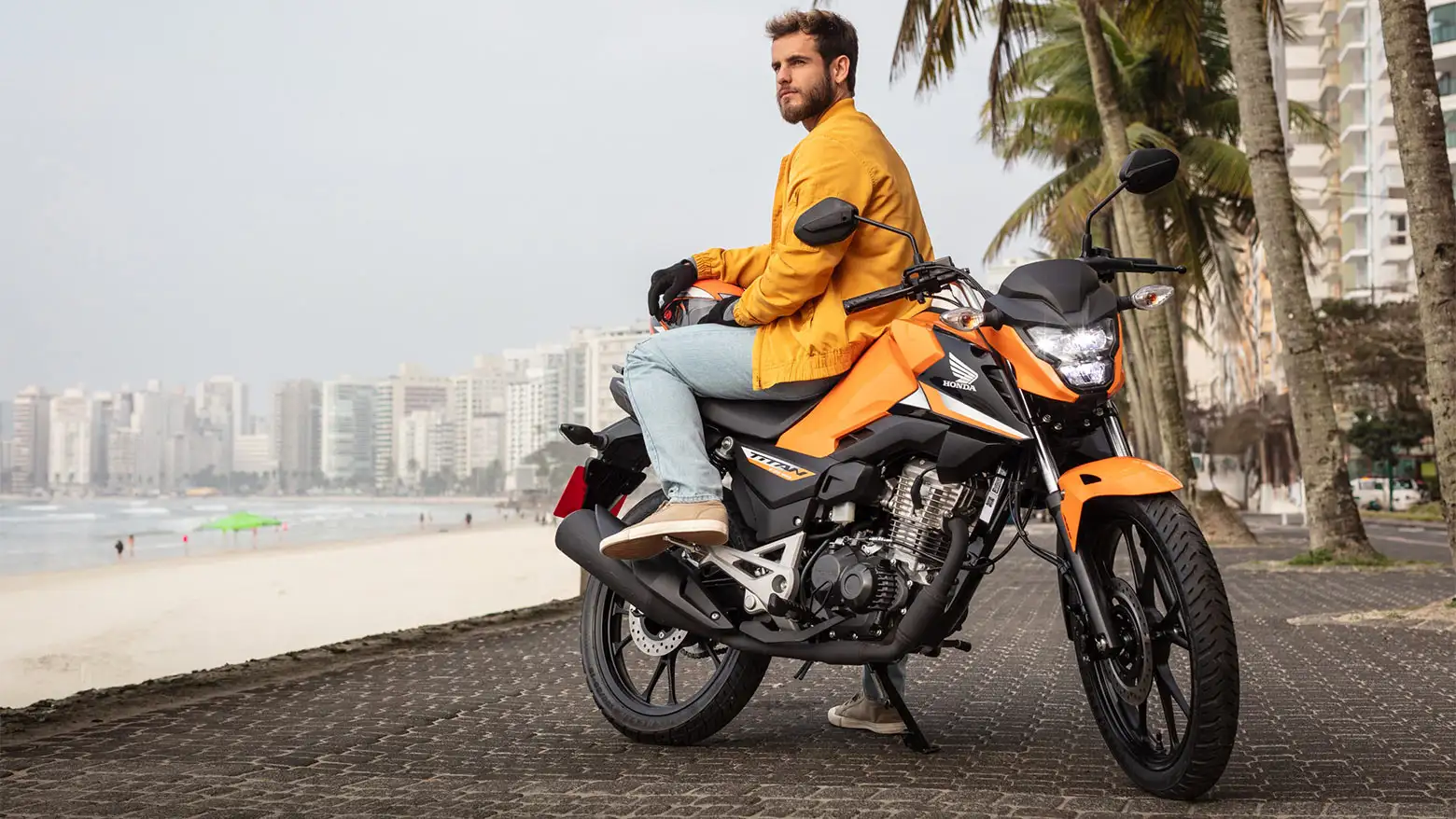 Homem observando a paisagem sentado na Honda CG 160 Titan laranja